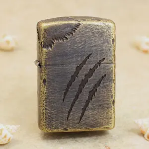 Leather-wrapped Zippo-style lighter with three claw-mark scratches on the front piece, on a sandy surface.