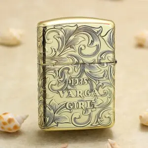 Gold-tone lighter with intricate scrollwork engraving reading '1935 VARGA GIRL'.