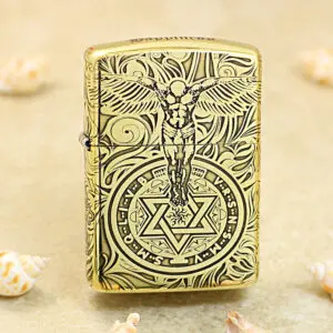Gold-tone Zippo lighter with black engraving of a winged figure above a circular mystical symbol with a six-pointed star.