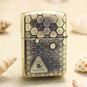 Brass Zippo-style lighter with a honeycomb hexagon pattern and a danger symbol on the front.