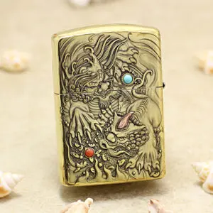 KZ248-01 Metal lighter with an ornate dragon relief and colored stone inlays on a sandy beach backdrop.
