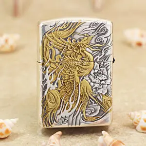 KZ282-01 Silver Zippo-style lighter with a detailed gold dragon engraving on a gray background, resting on sand with scattered seashells nearby.