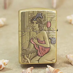 Gold-toned lighter engraved with a seated woman in a pink dress at a vanity against a geometric background.
