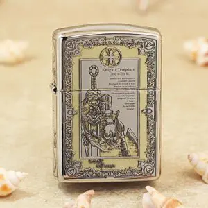 Metal lighter with an ornate Knights Templar engraving and decorative border on a beige surface