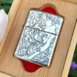 Angled front view of the arabesque woman sterling silver Zippo Armor lighter in a wooden display box