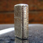 Close side view of sterling silver Zippo with vertical Latin inscription