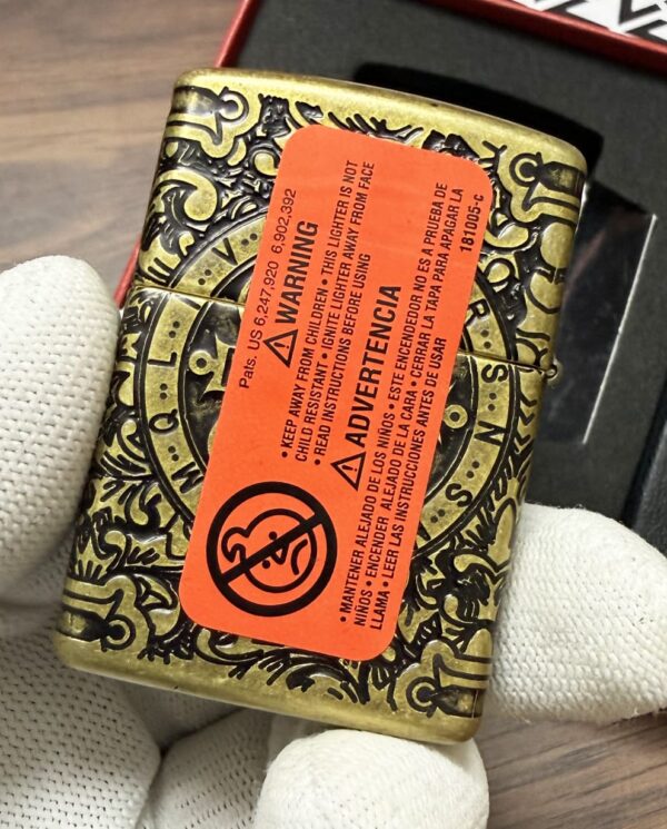 Ornate gold-and-black metal tin with an orange warning label held by gloved hands