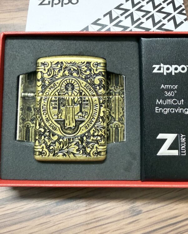 Brass Zippo lighter with ornate circular engraving in a red gift box.