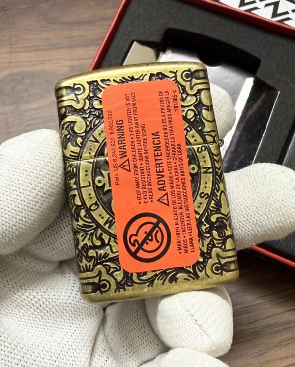 Ornate brass tin with a red warning label being held by gloved hands; decorative engraving on the container.