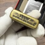 Brass Zippo lighter stamped 'Made in USA, Bradford, PA' held by gloved hand.