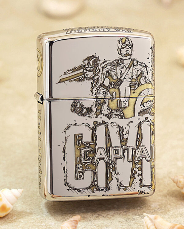 KZ142 Shiny Zippo lighter featuring a Captain America illustration and logo, resting on sandy surface with seashells nearby.