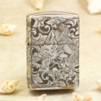 Silver lighter with an intricate black-and-white dragon and scrollwork engraving on its surface