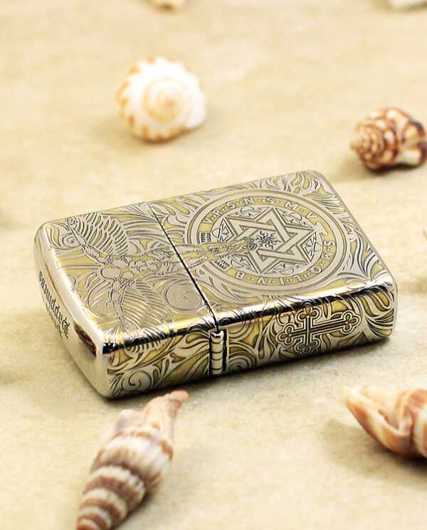 KZ145-04 Metallic engraved lighter lying on sand, surrounded by seashells on a beach.