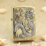 Polished brass Zippo Armor lighter with a geisha and coiling dragon engraved on the front