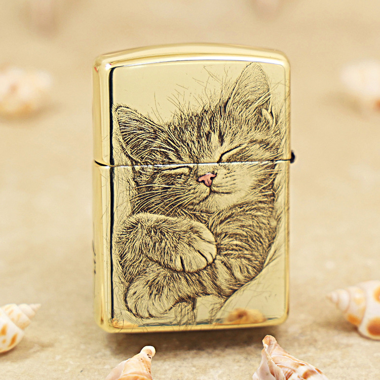 Gold Zippo lighter with a sleeping kitten illustration on the front.