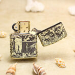 Decorative metal lighter with a black-on-cream illustration of people on a beach, placed on sand with seashells nearby.