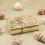 Gold engraved lighter on a sandy surface, featuring a mermaid among seaweed with seashells around it.