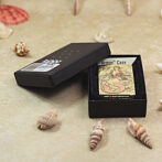 Open black gift box revealing a decorative mermaid-themed lighter labeled "Armor Case" on a sandy surface with seashells nearby.
