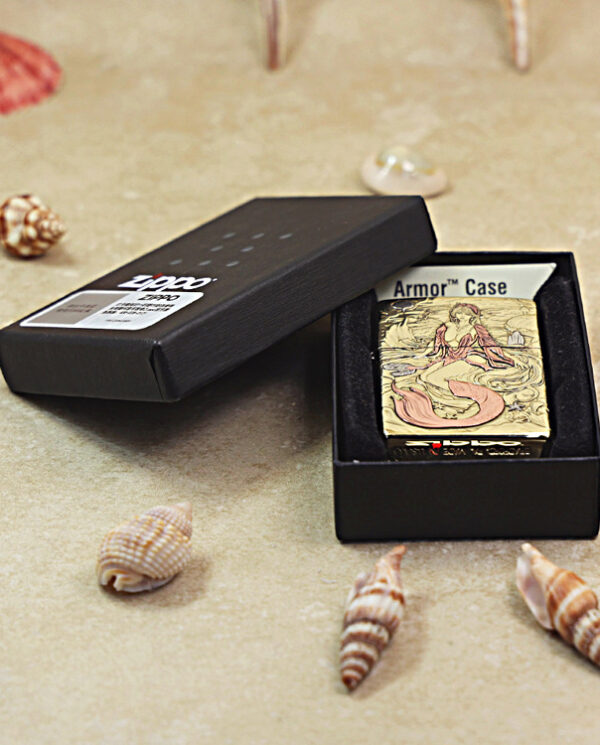 Open black gift box revealing a decorative mermaid-themed lighter labeled "Armor Case" on a sandy surface with seashells nearby.