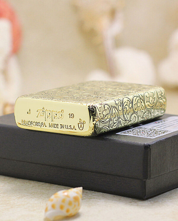 KZ159-05 Shiny Zippo lighter with an ornate swirling pattern resting on a black box.