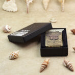 Brass Zippo lighter with Route 66 design in an open black presentation box, surrounded by seashells.