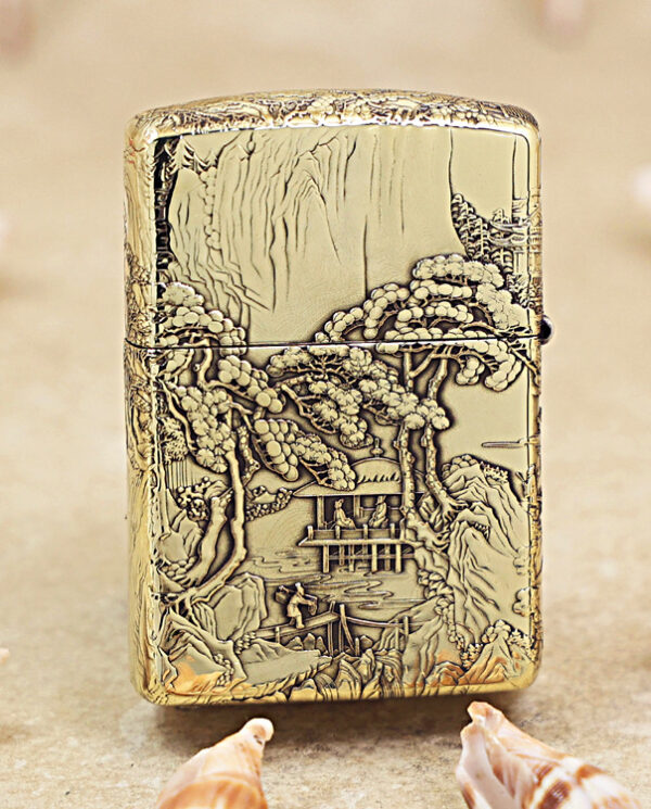KZ162-01 Gold engraved lighter with a detailed landscape scene of trees, a pavilion, and a boat on a river in relief artwork.