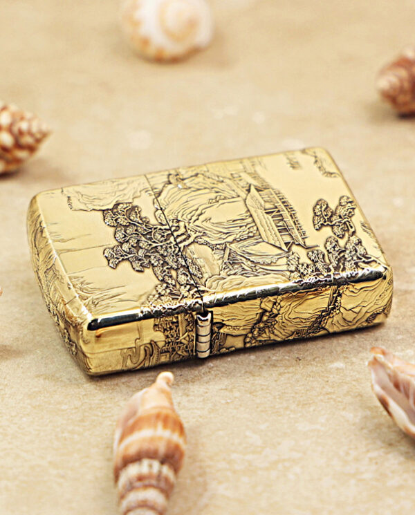 KZ162-04 Gold decorative metal box with an intricate embossed scene, placed on sand with seashells around it.