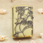 Gold Zippo lighter with ornate rose engravings and flowing vines in a decorative pattern.