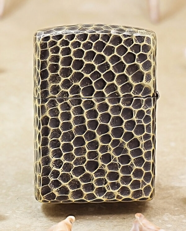 KZ175-01 Rectangular lighter with a black snakeskin pattern standing upright on a beige surface, surrounded by small seashells.