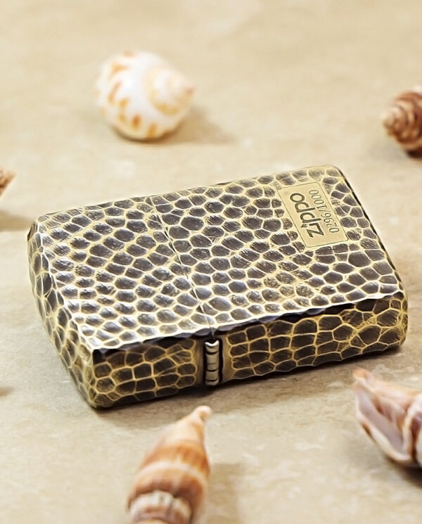 KZ175-04 Snakeskin-pattern Zippo lighter case on a beige surface, surrounded by seashells as décor