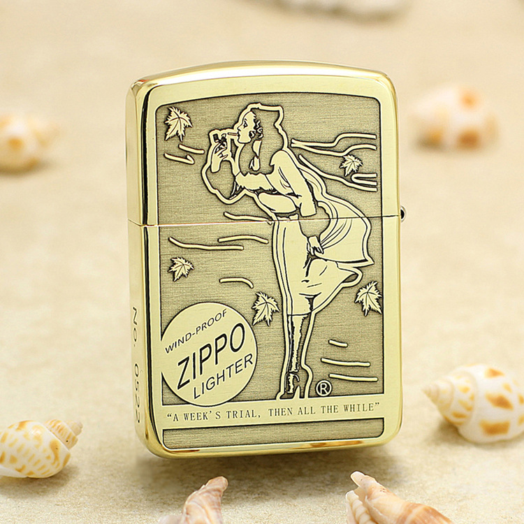 Vintage Zippo lighter standing upright on sandy surface with a retro engraving of a woman blowing a kiss; windproof design.