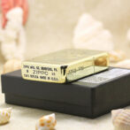 Gold Zippo lighter resting on a black box, stamped with 'Zippo Mfg. Co. Bradford, PA' and '1941 replica made in U.S.A.'