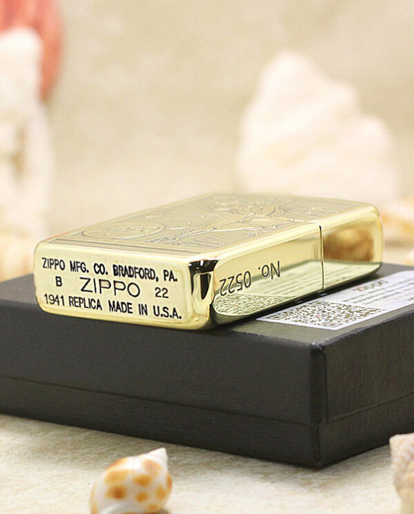KZ183-05 Gold Zippo lighter resting on a black box, stamped with 'Zippo Mfg. Co. Bradford, PA' and '1941 replica made in U.S.A.'