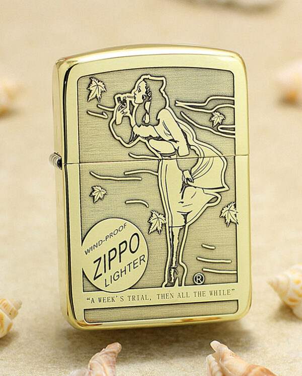 KZ183 Gold-tone Zippo lighter with an engraved seaside scene, featuring a woman by the wind-swept ocean and the words 'Zippo Lighter' on the case.