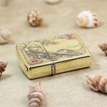 Katana woman engraved Zippo Armor lighter lying flat among seashells
