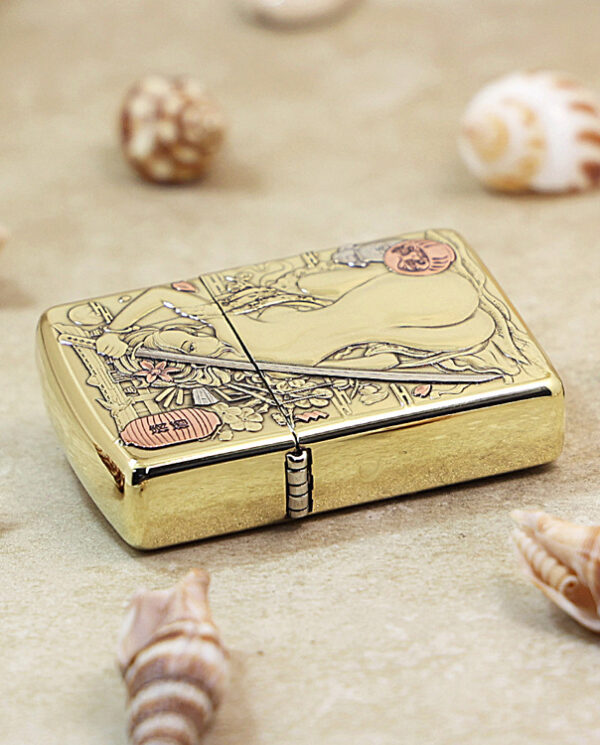 KZ189-04 Gold metal cigarette case with an engraved scene, resting on a sandy surface among seashells.