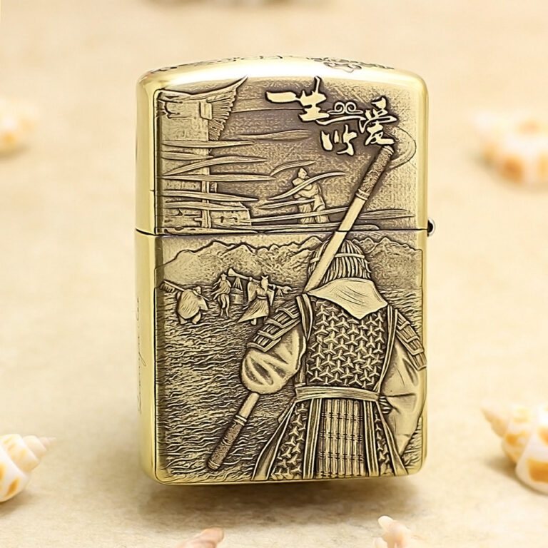Gold Zippo-style lighter with a backward-facing samurai in armor, holding a spear, set against a mountainous village scene in relief on the surface.