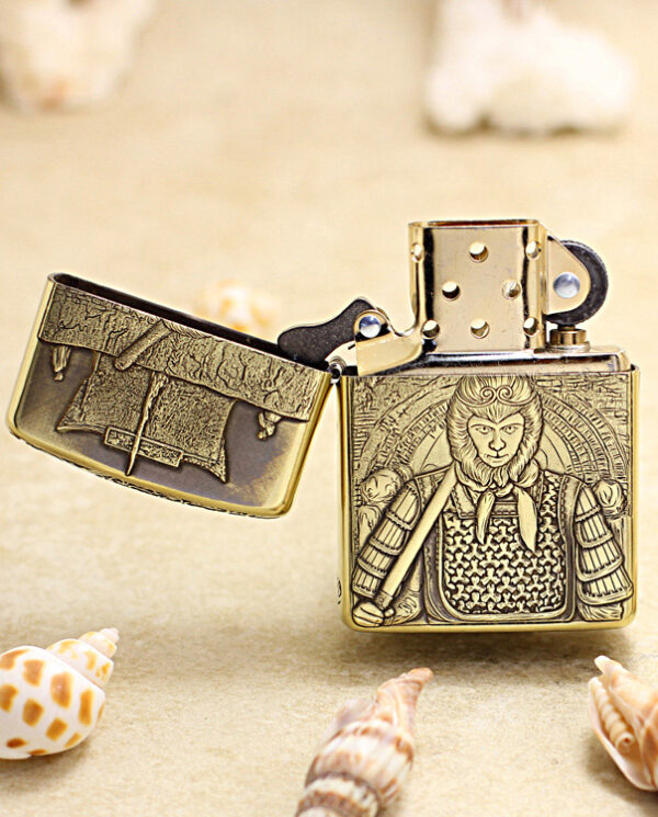 KZ190-02 Brass lighter with an engraved medieval knight on the front, lid open, resting on sandy surface with seashells nearby.