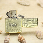 Gold-tone Zippo-style lighter with a camel engraving and 'Nutty Menthol' label, open lid on sandy beach among seashells.