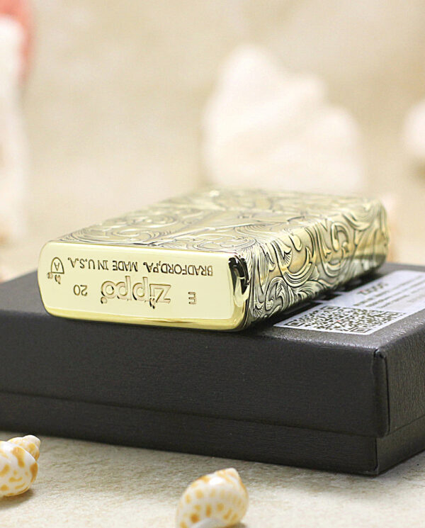 KZ202-05 Engraved Zippo lighter with ornate pattern sits on a black box, with small seashells and sandy surface in the foreground.