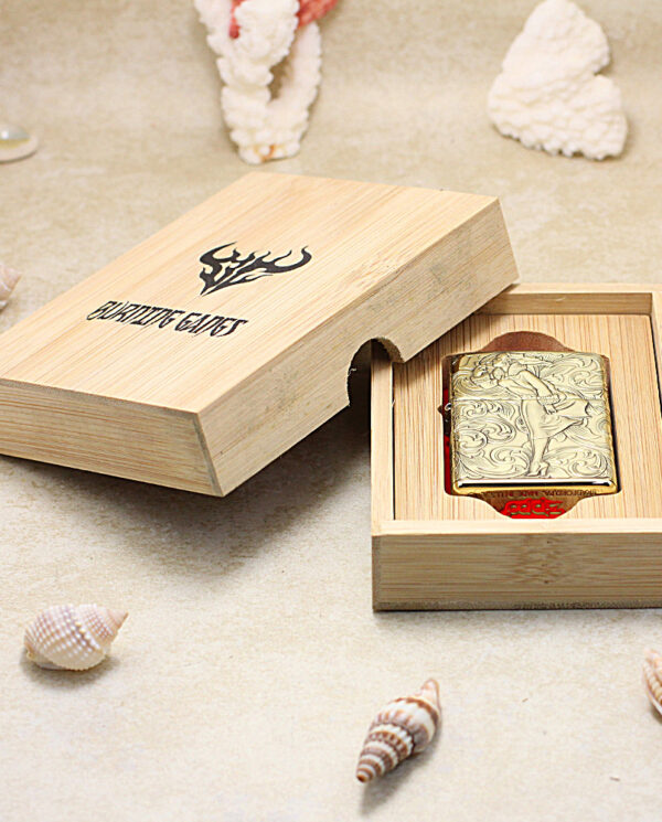 KZ202-06 Engraved Zippo lighter in an open wooden presentation box on a sandy surface with seashells nearby.