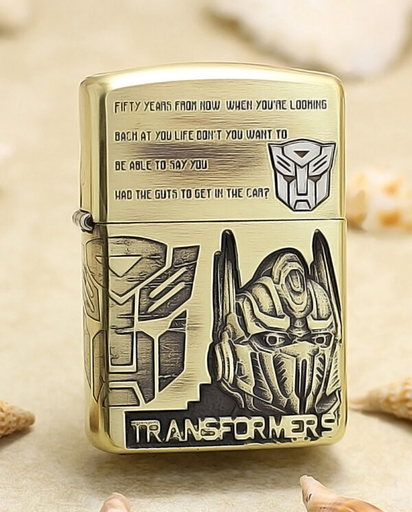 KZ206 Gold-tone lighter decorated with Transformers artwork, featuring a geometric panel design and a robotic helmet, plus the word Transformers on the front.