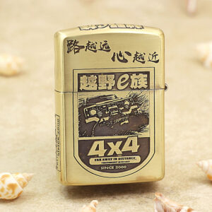 Gold Zippo lighter with a black-and-white 4x4 off-road graphic and Chinese characters, resting on a sandy surface.