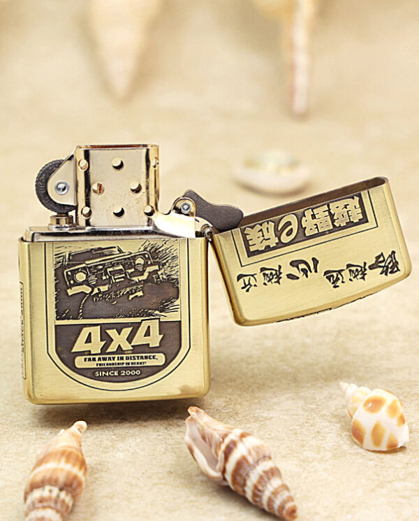 KZ209-03 Gold metal lighter open on a sandy beach, surrounded by seashells, displaying a 4x4 badge on its front.