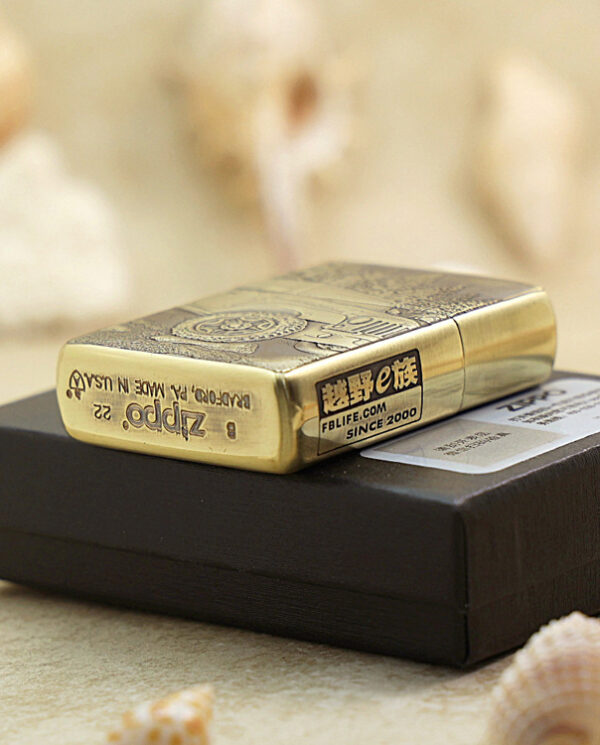 KZ209-05 Gold brass Zippo lighter with engravings resting on a black box, surrounded by seashells.