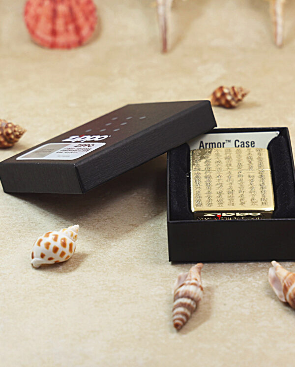 KZ213-06 Gold-engraved Zippo-style lighter in a black gift box, surrounded by seashells on a beige surface, open to reveal the engraving