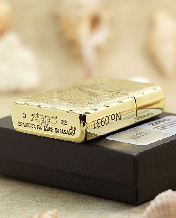 KZ214-05 Gold Zippo lighter with an engraved design resting on a black display box, reflecting light off its polished surface (product shot).