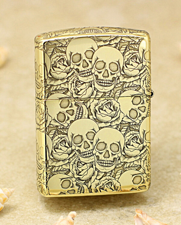 KZ215-01 Gold lighter with a raised skulls and roses engraving on a gold surface, decorative pattern across the entire body