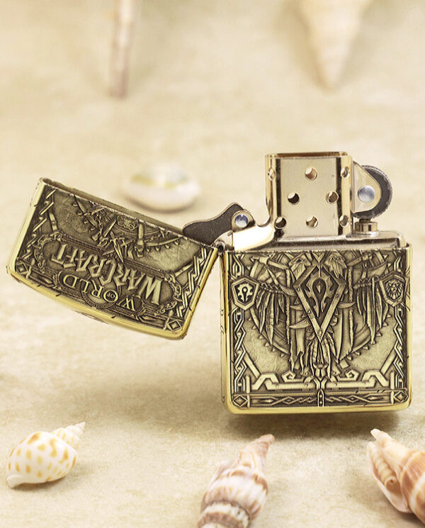 KZ217-02 Open Zippo-style lighter with intricate medieval engravings on a sandy surface with seashells nearby.
