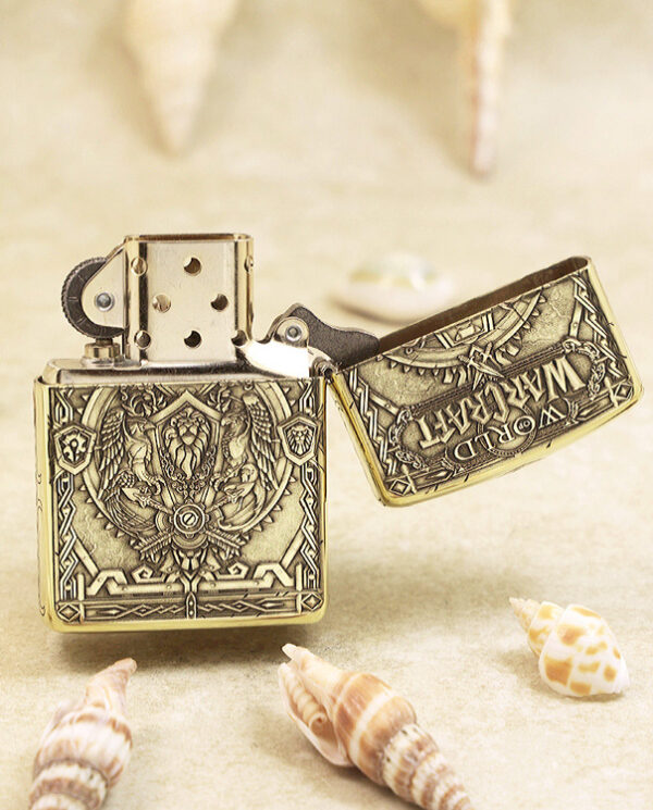 KZ217-03 Ornate metal Zippo lighter open on a sandy surface with seashells around.